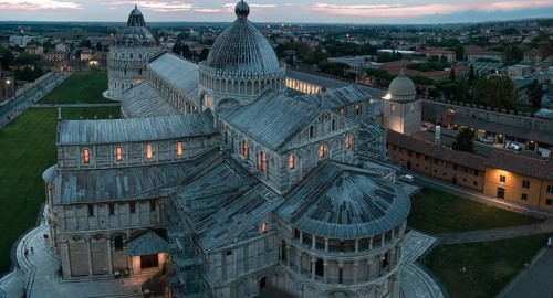View of the illuminated Cathedral of Santa Maria Assunta with several domes at dusk with an