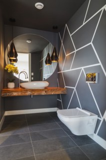 White wall-mounted toilet and thick varnished maple wood countertop with vessel sink and round