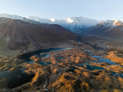 Atmospheric aerial view, high mountain landscape with glacier moraines and mountain lakes, behind