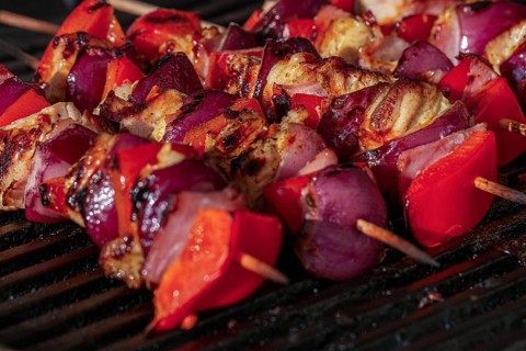 Grilled skewers with Sweet peppers, onions and pieces of chicken on a charcoal grill with visible