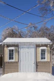 Storage shed facade and overhead electrical wires covered in thick ice and snow in residential