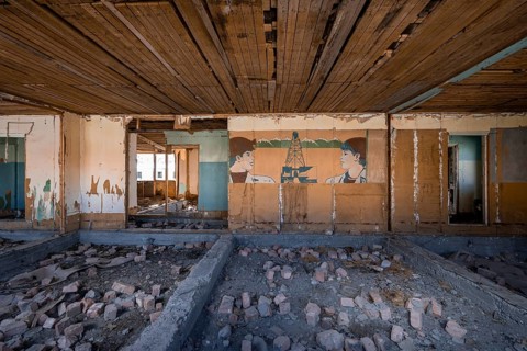 Destroyed abandoned classroom of the old school, wall painting with Soviet miners, ghost town,