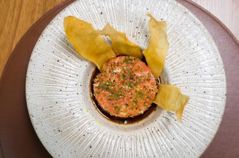 PERUVIAN FOOD. Spiced Salmon Ceviche with Chives and Lime on a white plate served with Fried Sweet