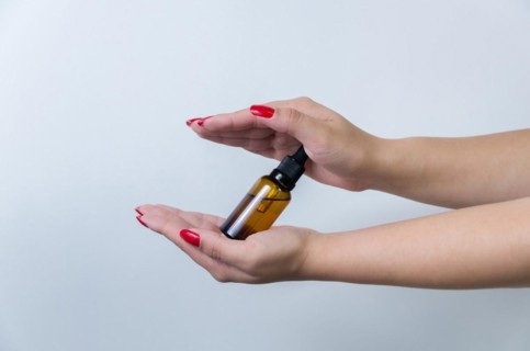 Product package with serum and a woman hand in studio on a background to promote an antiaging