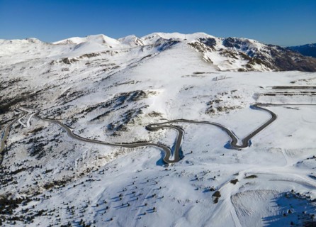 Aerial view of a winding mountain road through a wintry snowy landscape View from Grau Roig in the
