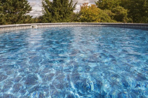 Above ground swimming pool surrounded by deciduous trees in residential backyard, Quebec, Canada,