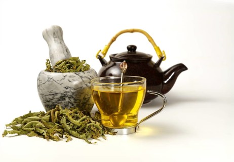 Lemon verbena infusion in a glass cup with a marble mortar and pestle and a ceramic teapot with
