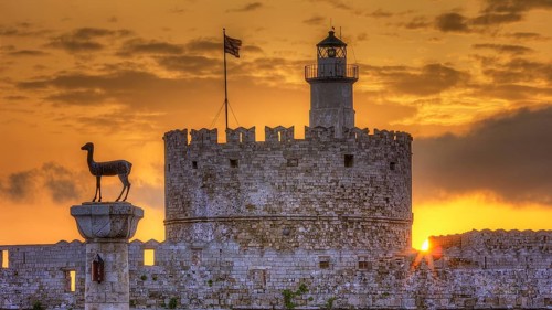 A statue on the top of a fortress wall with a golden sunrise, sunrise, dawn, Fort of Saint