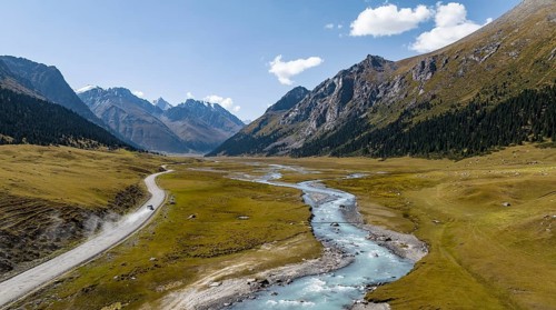 Car on road, mountain river in green mountain valley in the Tien Shan Mountains, Jety Oguz,