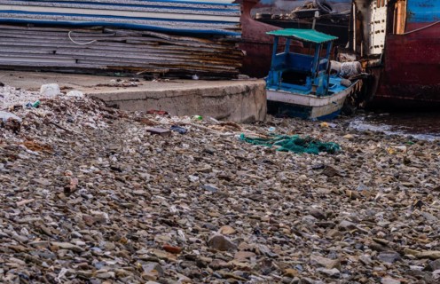 Old rusty abandoned ships sitting on the shore amid trash and debris at a marine junkyard in South