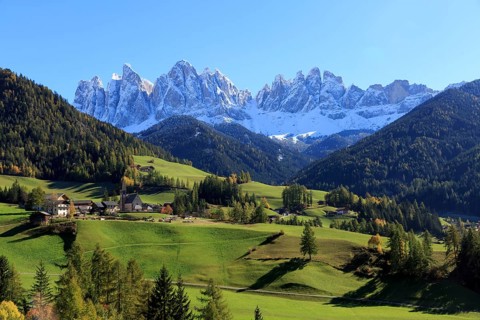 Sunny view of an alpine village with green meadows and mountain panorama, Italy, Trentino-Alto