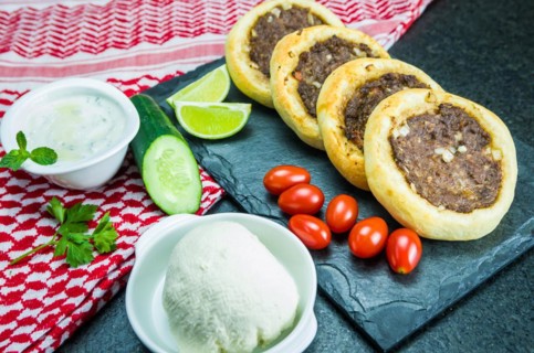Delicious Lebanese (Arabic) food, genuine sfihas on a slate plate with tomatoes, lemons and labneh