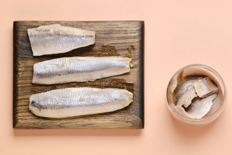 Top view of marinated clupeidae on cutting board and glass jar