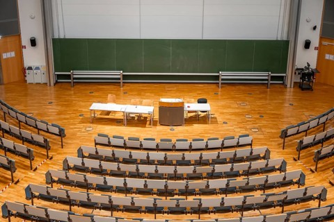 View from above into an empty lecture theatre with rows of seats and lectern, interior photo,