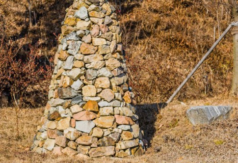 Closeup of pile of stones in the shape of an upside down cone in a public road side park near