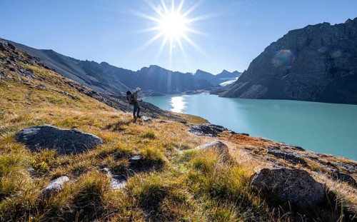 Mountaineers at the turquoise Ala Kul mountain lake in the morning light, Sun Star, Tien Shan