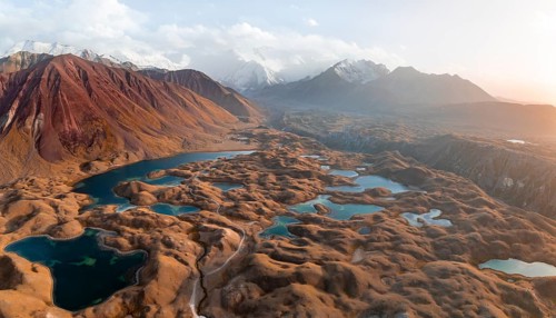 Atmospheric aerial view, high mountain landscape with glacier moraines and mountain lakes, behind