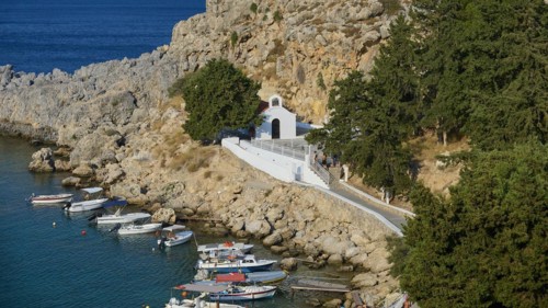Small church on a rocky path surrounded by boats on a clear sea, St Paul's Chapel, Paul's Bay,