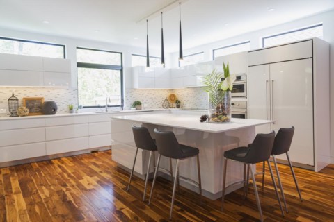 White high-gloss lacquered cabinets and island with grey leather bar stools and white quartz