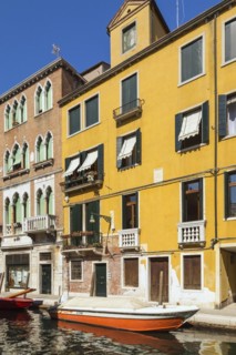 Narrow canal with moored boats and Renaissance architectural style residential palace buildings,