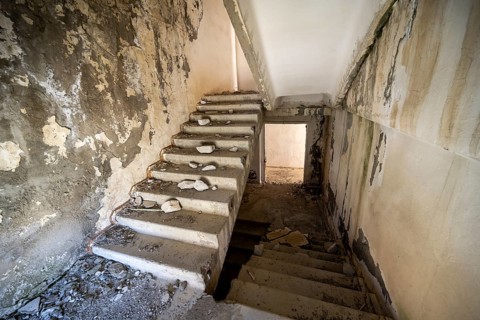 A crumbling staircase in an abandoned building with peeling paint and visible decay, ghost town,