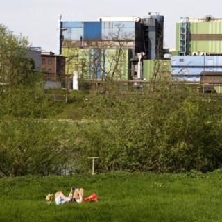 Couple lies on the Ruhrauen in front of the stainless steel plant in Witten, Ruhr area, North
