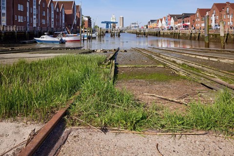 Old rusty rails with grass of the slipway of the old shipyard in the harbour of Husum, district of
