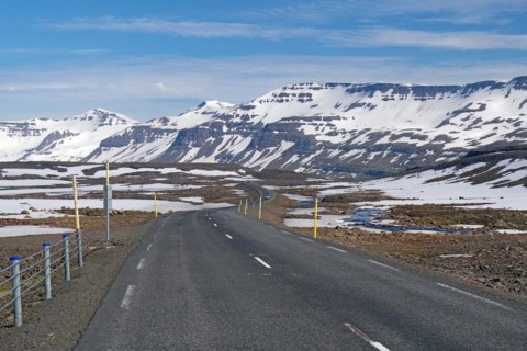 Road leads through barren mountain landscape with snow and ice, Seydisfjoerdur, Fjaroarheioi,