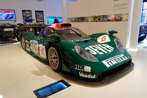 PORSCHE 911 GTI 98, front view of a green Porsche racing car with sponsor logo in a showroom,