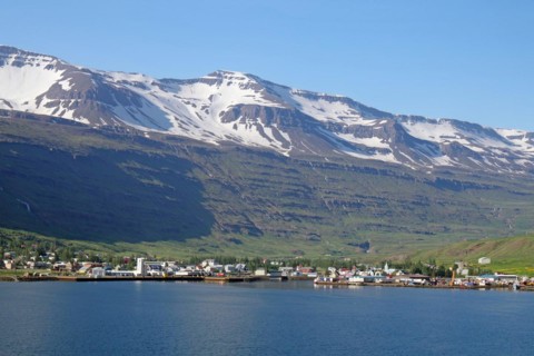 Small village under snow-covered, rugged mountains, ferry town, Seydisfjoerdur, East Iceland,