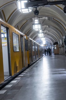 A yellow underground train stops at an arched platform underground, Heidelberger Platz, Berlin,