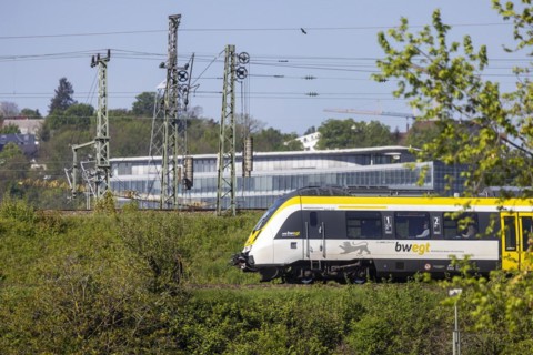 Regional train of the mobility brand bwegt unterwegs, railway embankment and overhead lines,