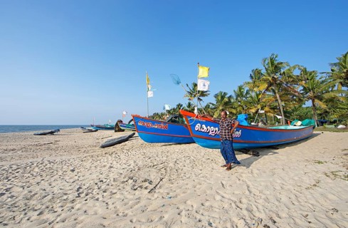Indian fisherman, 42 years old, and colourful fishing boats at Marari Beach or beach, Mararikulam,