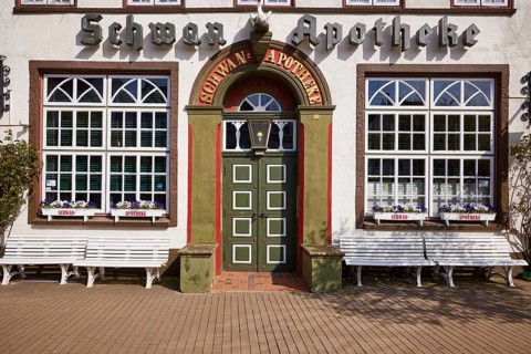 Entrance door of the Swan pharmacy with windows, flower boxes and benches in the city centre of