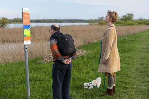 Man and woman reading sign, information board, dog, Elbtalaue near Bleckede, Lower Saxony, Germany,