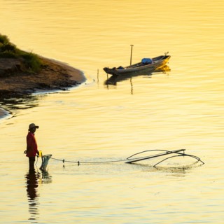 Fisherman with a sinking net at sunset on the Mekong, Luang Prabang, Laos, Asia