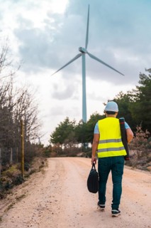 Vertical photo of the rear view of a male caucasian adult engineer walking along a path of green
