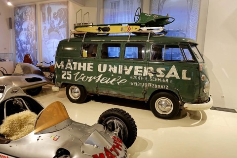 VW Transporter T1, Green Volkswagen bus with roof rack and surfboard in a car museum, AUTOMUSEUM