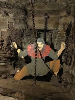 Figurative depicted torture scene of torture with put in chains in small torture museum in tower