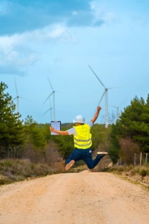 Vertical rear view of a male caucasian adult engineer celebrating jumping on air next to wind