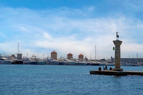 Deer Elafos, sculpture on a column, at the entrance to the harbour, in the background the three