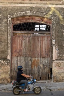 Fat woman on a moped in front of an old warehouse, rural scene in Victoria, Duck, Argentina, South