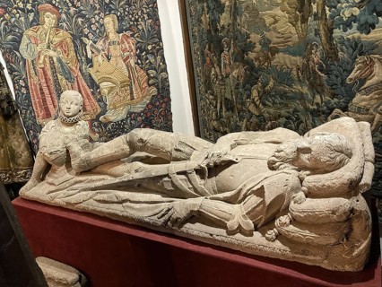 Exhibit historical tomb slab of knight nobleman in the background old historical tapestry