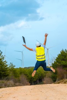 Worker jumping and raising arms in a path in a green energy park