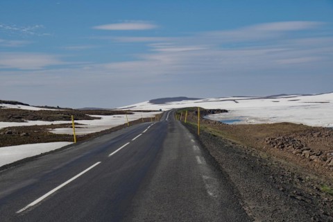 Road leads through barren mountain landscape with snow and ice, Seydisfjoerdur, Fjaroarheioi,