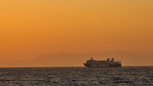 A ferry sails on the sea under a golden sunset sky, dusk, sunset, Western Promenade, Rhodes Town,