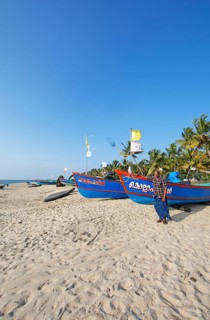 Indian fisherman, 42 years old, and colourful fishing boats at Marari Beach or beach, Mararikulam,