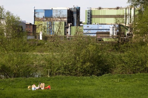 Couple lies on the Ruhrauen in front of the stainless steel plant in Witten, Ruhr area, North