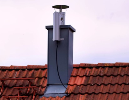Retrofitted chimney on roof, with dust separator, electrostatic filtering of soot particles from