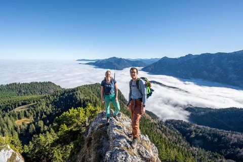 Two hikers at Ettaler Manndl, view over mountain landscape and sea of clouds, high fog in the